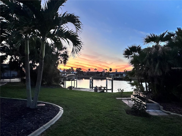 view of dock with a lawn, a water view, and boat lift