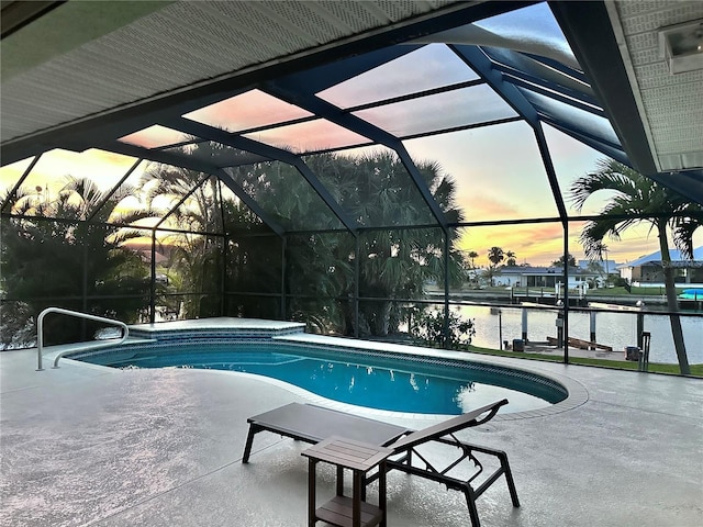 pool at dusk with a lanai, a patio area, a water view, and an outdoor pool