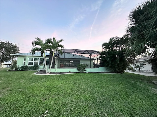 back of property featuring glass enclosure and a yard