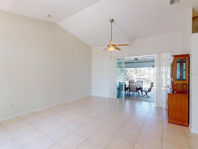 spare room featuring lofted ceiling, light tile patterned floors, a ceiling fan, and baseboards