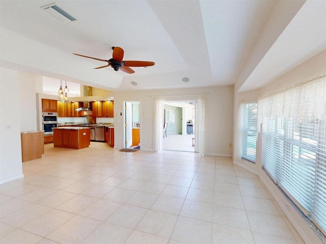 living room featuring light tile patterned floors, baseboards, visible vents, a tray ceiling, and ceiling fan with notable chandelier