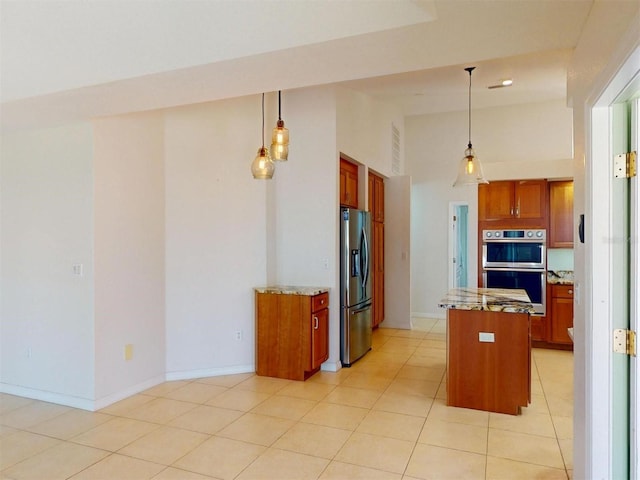 kitchen featuring appliances with stainless steel finishes, brown cabinets, light stone countertops, and a center island