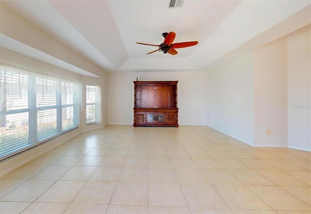 spare room featuring a tray ceiling, light tile patterned flooring, visible vents, and baseboards