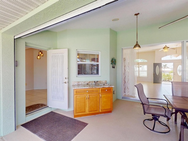 kitchen featuring light stone counters, brown cabinetry, a ceiling fan, and decorative light fixtures