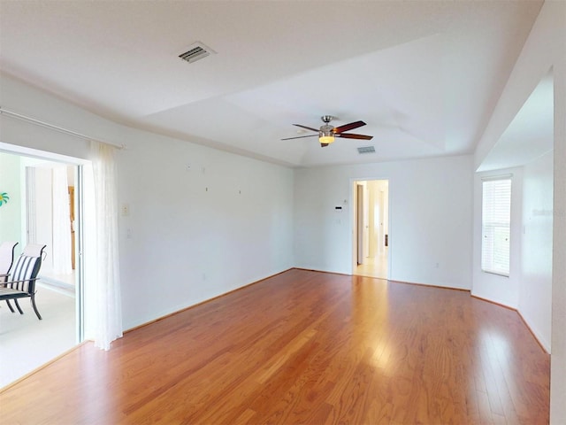 empty room with a ceiling fan, light wood-type flooring, and visible vents