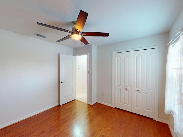 unfurnished bedroom featuring a closet, visible vents, baseboards, and wood finished floors