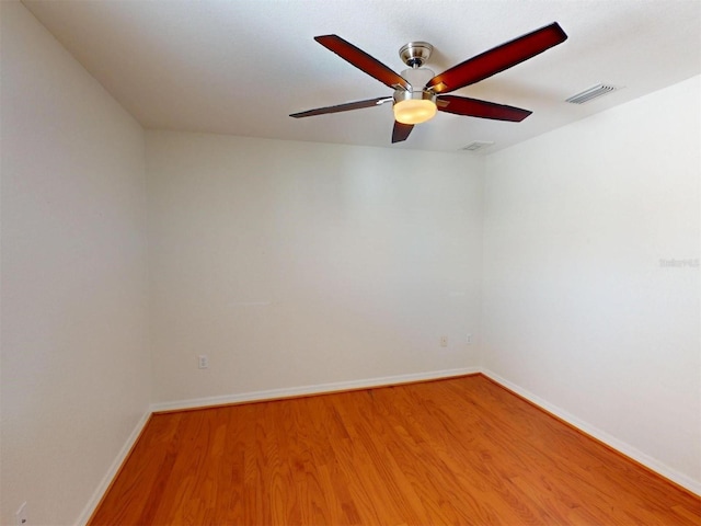 empty room with a ceiling fan, baseboards, visible vents, and wood finished floors