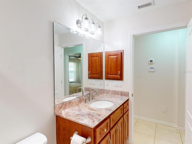 bathroom featuring toilet, vanity, baseboards, visible vents, and tile patterned floors