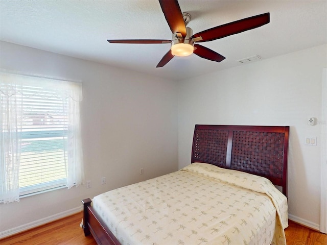 bedroom featuring light wood-style floors, visible vents, baseboards, and a ceiling fan