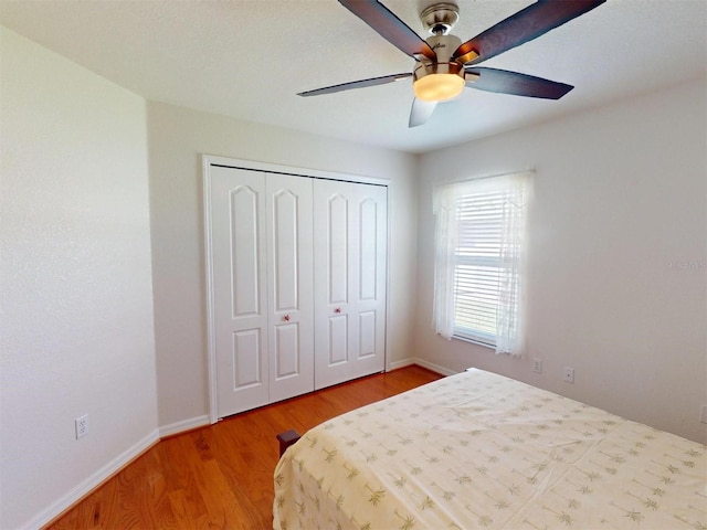 bedroom featuring a closet, ceiling fan, light wood-style flooring, and baseboards