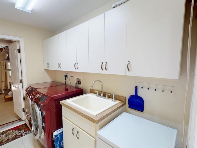 washroom with a sink, washing machine and clothes dryer, cabinet space, and tile patterned floors