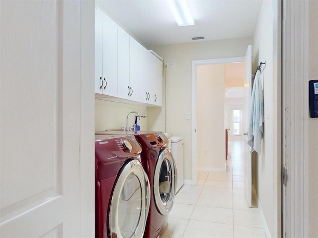 laundry area featuring light tile patterned floors, separate washer and dryer, visible vents, baseboards, and cabinet space