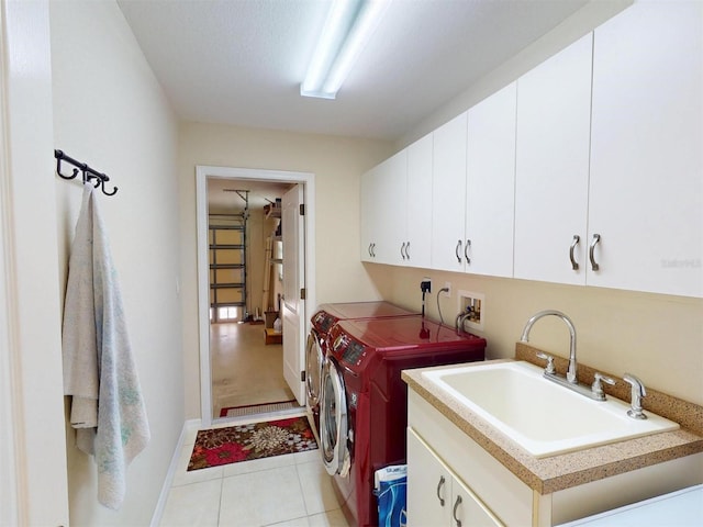 washroom with cabinet space, light tile patterned floors, separate washer and dryer, and a sink