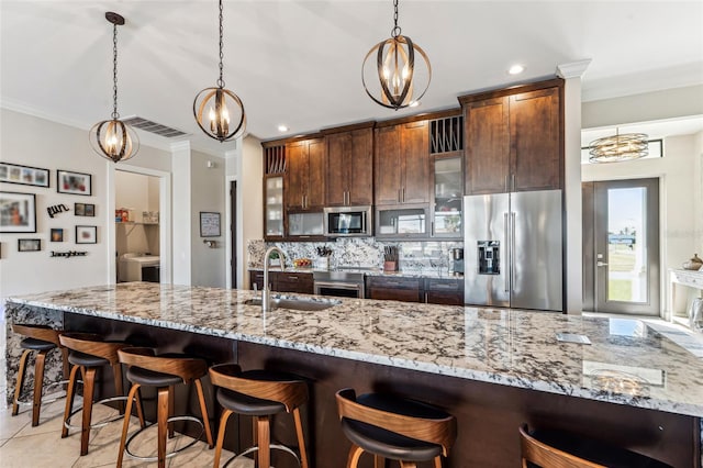 kitchen featuring visible vents, decorative backsplash, glass insert cabinets, appliances with stainless steel finishes, and a sink