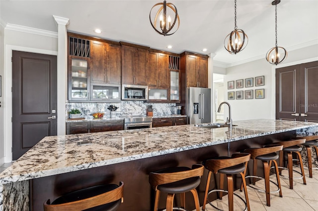 kitchen featuring glass insert cabinets, crown molding, appliances with stainless steel finishes, and a kitchen bar