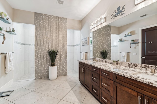 bathroom with double vanity, visible vents, walk in shower, and a sink