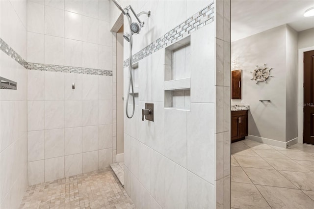 bathroom featuring tile patterned floors, baseboards, walk in shower, and vanity