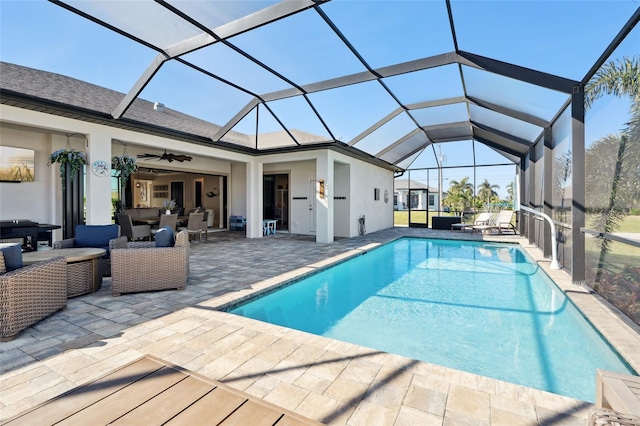 outdoor pool with glass enclosure, ceiling fan, outdoor lounge area, and a patio