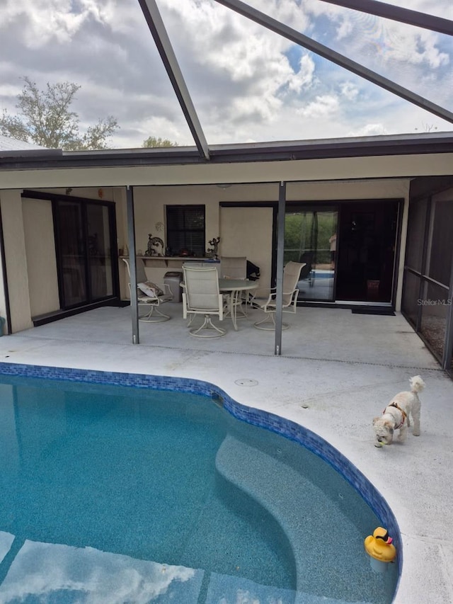 pool with glass enclosure and a patio area