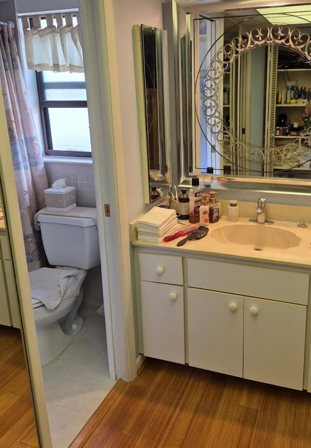 half bathroom featuring toilet, wood finished floors, and vanity