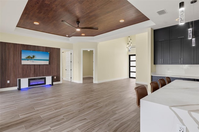 interior space featuring ceiling fan, wooden ceiling, light hardwood / wood-style floors, and a raised ceiling