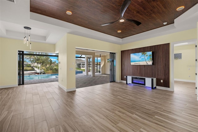 interior space featuring ceiling fan, light wood-type flooring, a raised ceiling, and wooden ceiling