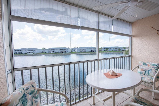 sunroom / solarium featuring a water view, a residential view, and a ceiling fan