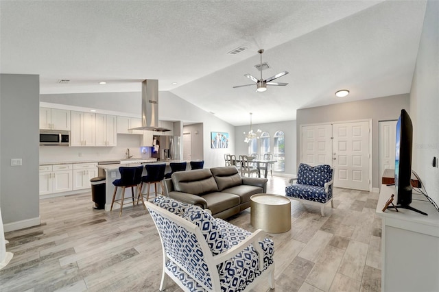 living room featuring light hardwood / wood-style flooring, ceiling fan, a textured ceiling, and lofted ceiling