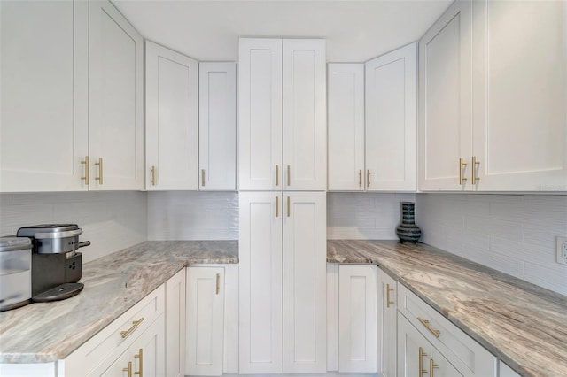 kitchen with white cabinets, light stone countertops, and decorative backsplash