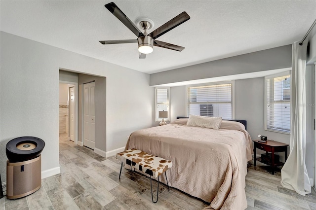 bedroom with light wood-type flooring, multiple windows, and a textured ceiling