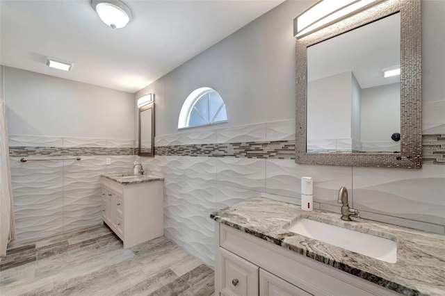 bathroom with tile walls, vanity, and wood-type flooring