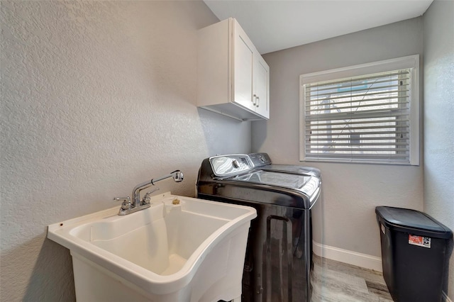 laundry area featuring sink, cabinets, light hardwood / wood-style floors, and washer and dryer