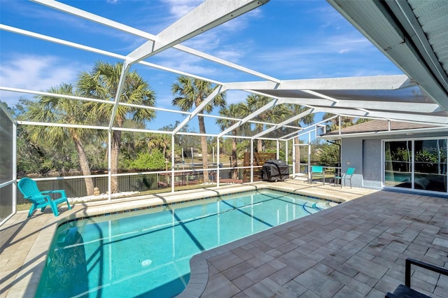 view of swimming pool with glass enclosure, a grill, and a patio area