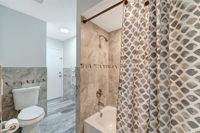 bathroom featuring tile walls, wood-type flooring, shower / tub combo, and toilet