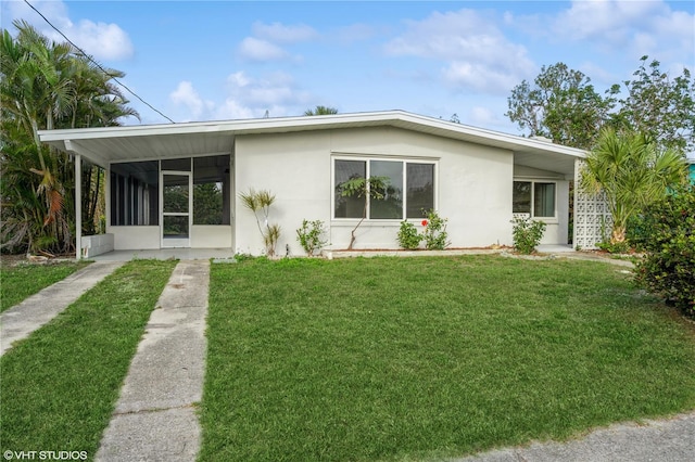 rear view of house featuring a sunroom, a lawn, and stucco siding