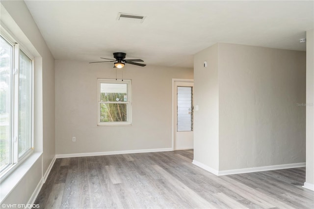 empty room featuring ceiling fan, light wood-style flooring, visible vents, and baseboards