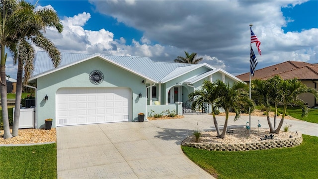 ranch-style house with a garage, metal roof, decorative driveway, and stucco siding