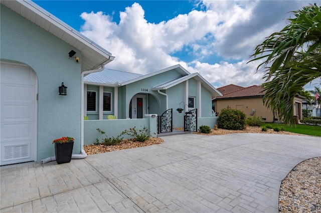 view of front of property with a garage, a fenced front yard, a gate, and stucco siding