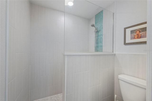 bathroom with toilet, a walk in shower, and tile walls