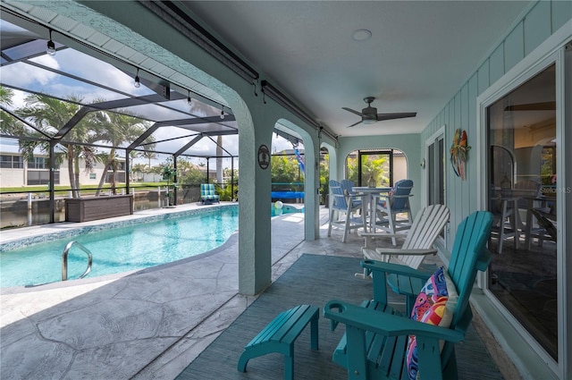 pool with glass enclosure, ceiling fan, and a patio