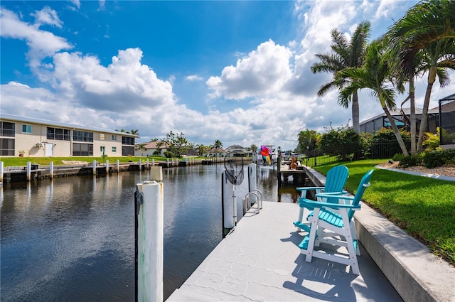 view of dock with a lawn and a water view