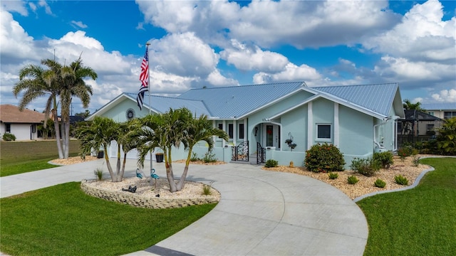 single story home featuring a front yard, metal roof, and curved driveway