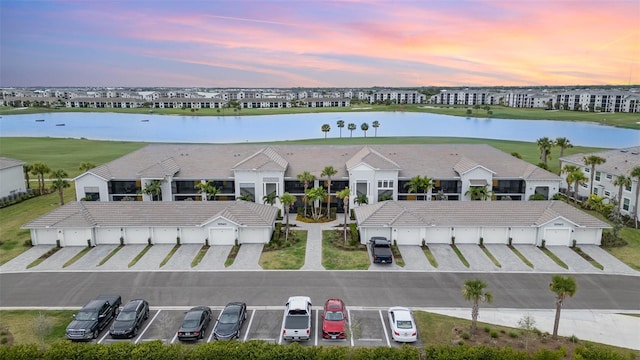 aerial view at dusk featuring a water view and a residential view