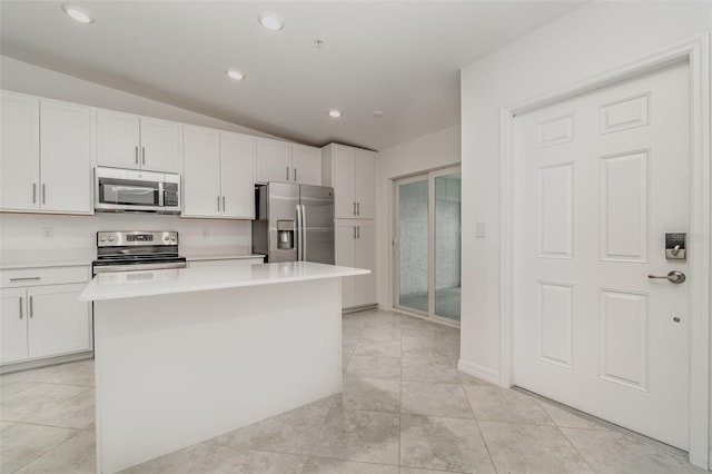 kitchen featuring light tile patterned flooring, stainless steel appliances, white cabinets, light countertops, and a center island