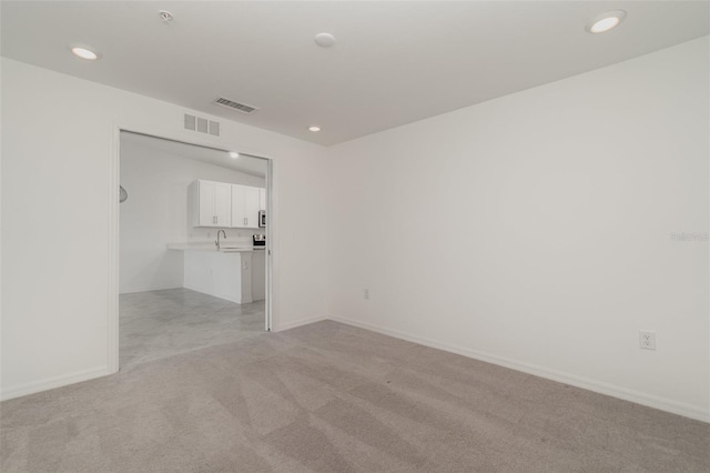 empty room featuring light carpet, baseboards, visible vents, and recessed lighting