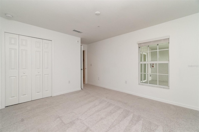 unfurnished bedroom with carpet floors, a closet, visible vents, and baseboards