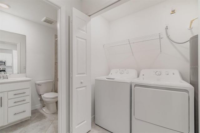 washroom with light tile patterned flooring, laundry area, a sink, visible vents, and washer and clothes dryer