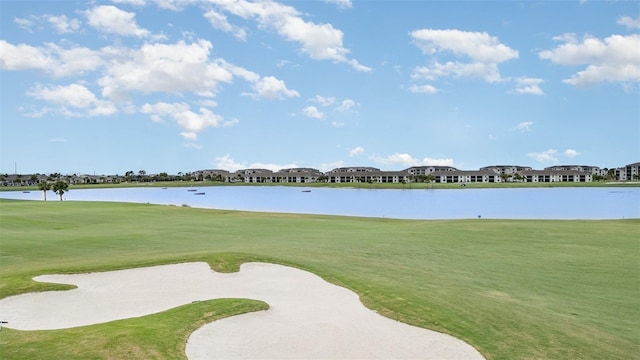 surrounding community with view of golf course, a lawn, and a water view