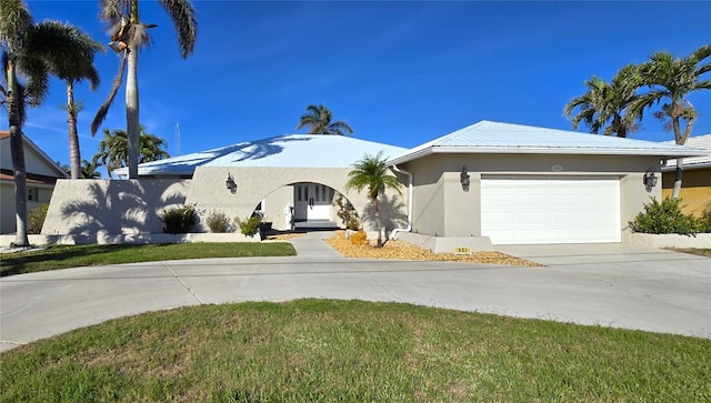 view of front facade featuring a garage, driveway, a front yard, and stucco siding