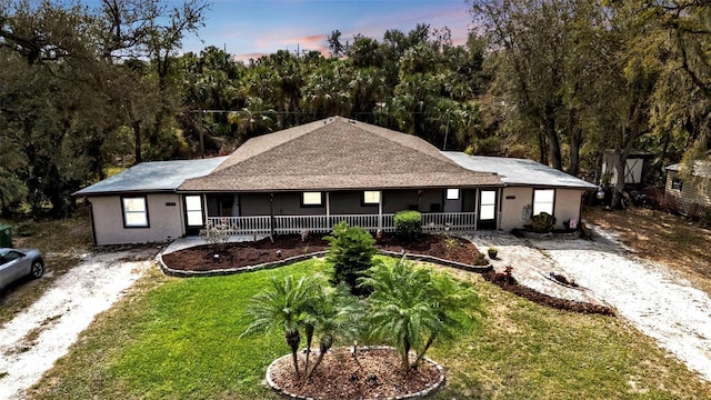 single story home featuring driveway, a porch, and a lawn